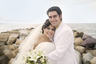 Hispanic bride and groom hugging