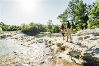 Caucasian couple walking on rocks near river