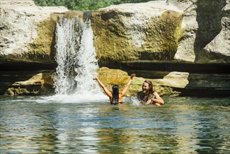Caucasian couple swimming near waterfall