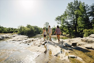 Friends walking on rocks near river