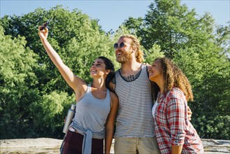 Friends posing for cell phone selfie outdoors