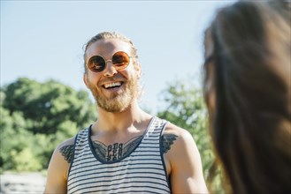 Caucasian man with chest tattoo laughing outdoors