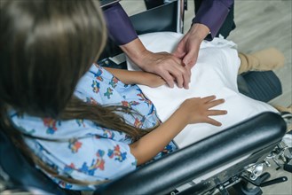 Doctor holding hands with girl in a wheelchair