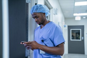 Black nurse texting on cell phone