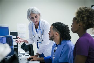 Doctor talking to nurses at computer