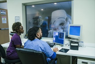 Nurses using computer near scanner