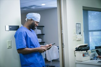 Smiling black nurse using digital tablet