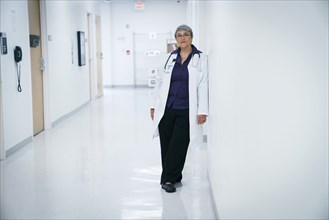 Mixed race doctor leaning on hospital wall