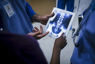 Doctors examining x-ray of pelvis and spine on digital tablet