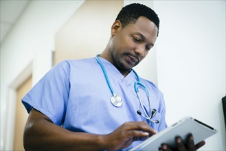 Black nurse using digital tablet in hospital