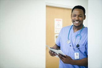 Portrait of smiling black nurse holding digital tablet