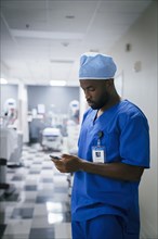 Black nurse texting on cell phone in hospital