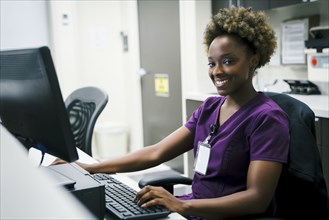 Portrait of smiling black nurse using computer