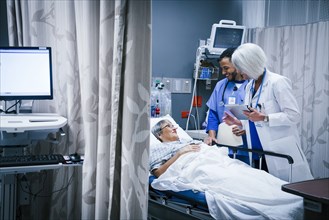 Doctor and nurse talking with patient in hospital bed