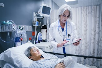 Doctor with digital tablet talking to patient