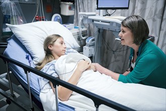 Caucasian doctor comforting patient in hospital bed