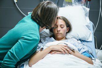 Caucasian mother kissing your daughter on forehead in hospital