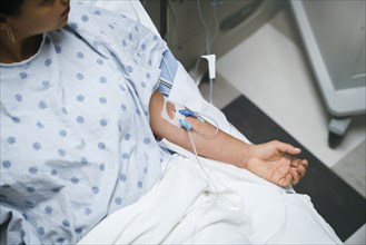 Tubes in arms of patient in hospital bed