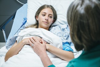 Doctor comforting Caucasian girl laying in hospital bed