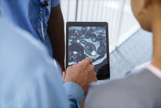 Close up of doctor and nurses viewing image on digital tablet