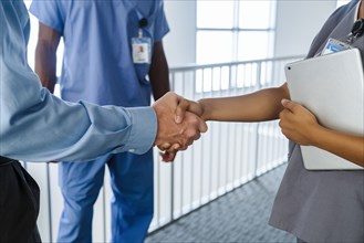 Doctor and nurse shaking hands near railing