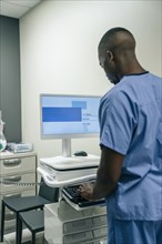 Black doctor using computer in hospital