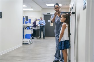 Nurse measuring height of girl in hospital