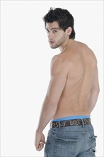 Bare-chested Hispanic man looking over shoulder