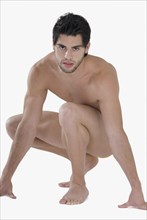 Nude Hispanic man crouching