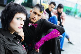 Group of punk Hispanic teenagers sitting on urban sidewalk