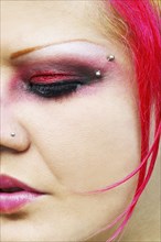 Close up of Hispanic woman with vibrant make-up and facial piercings