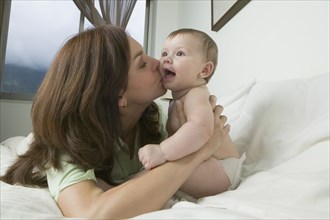 Hispanic mother kissing baby