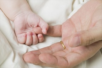 Close up of baby holding father's finger
