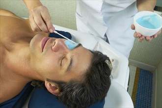 Hispanic man receiving spa facial treatment