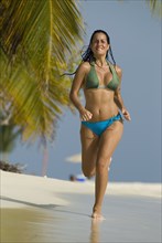 Hispanic woman jogging on beach