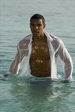 Hispanic man wearing clothing in water