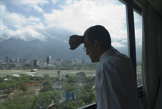 Hispanic businessman looking out window