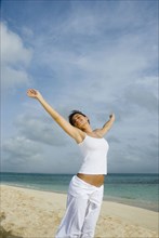 Woman with arms raised at beach