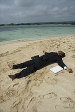 Hispanic businessman laying on beach