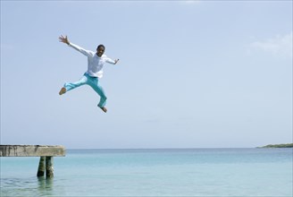 Hispanic man jumping off dock