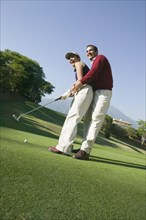 Hispanic couple playing golf