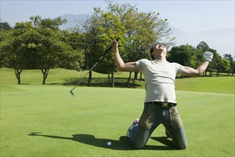 Asian man cheering on golf course