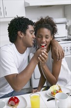 African man feeding fruit to girlfriend