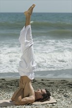Hispanic man doing yoga at beach