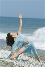 Hispanic woman doing yoga at beach