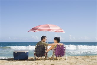Hispanic couple relaxing at beach