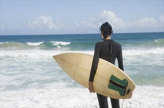 Hispanic woman at beach with surfboard
