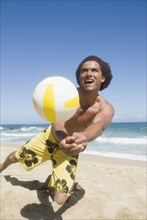 African man playing volleyball at beach
