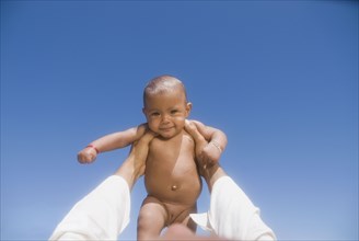 African man lifting nude baby girl