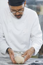 Baker working with dough in bakery kitchen